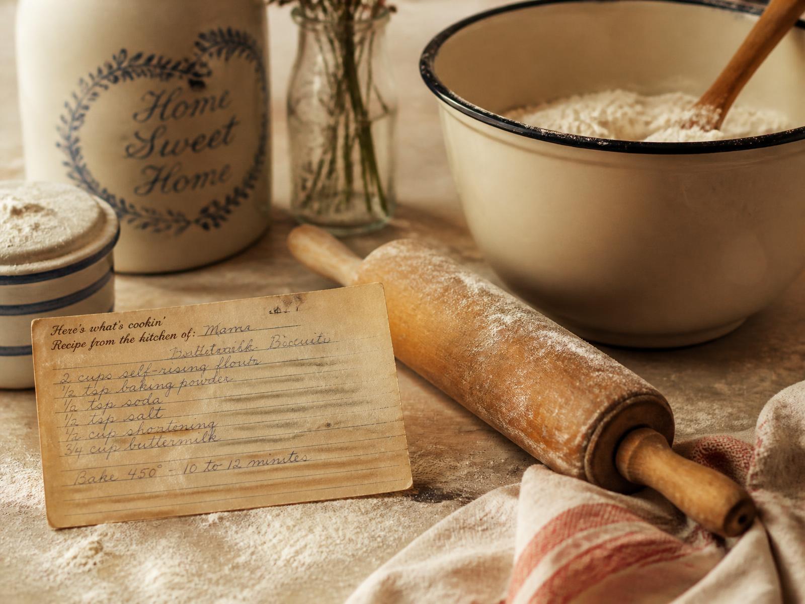Handwritten family recipe card beside a vintage rolling pin and flour